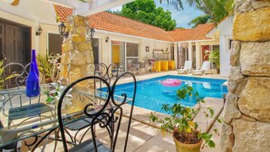 A pool area with a clear blue pool, lounge chairs, and a stone wall. - 4-Bedroom Villa with an Exclusive Private Pool, Sleeps 8 (playa del carmen)