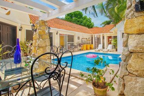 A pool area with a clear blue pool, lounge chairs, and a stone wall. - 4-Bedroom Villa with an Exclusive Private Pool, Sleeps 8 (playa del carmen)