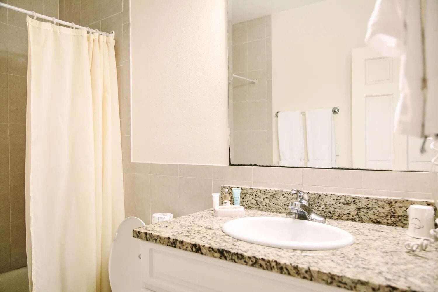 A bathroom with a white sink, granite countertop, and a mirror above the sink.