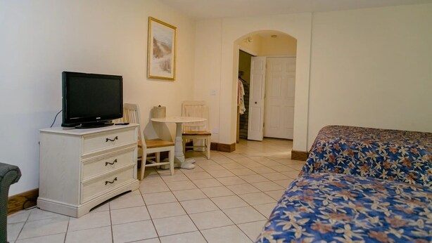 Ein Hotelzimmer mit einem Bett, einem Fernseher auf einer Kommode, einem kleinen Tisch und einem Stuhl.