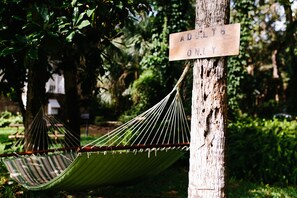 Una hamaca atada a un árbol con un letrero que dice 'ADULTOS SOLAMENTE'.
