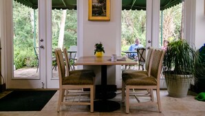Ein Essbereich mit Tisch, Stühlen, einem gerahmten Bild und einem Blumentopf.