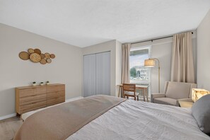 Une chambre à coucher comprenant un lit, un bureau, une chaise, une armoire et une lampe.