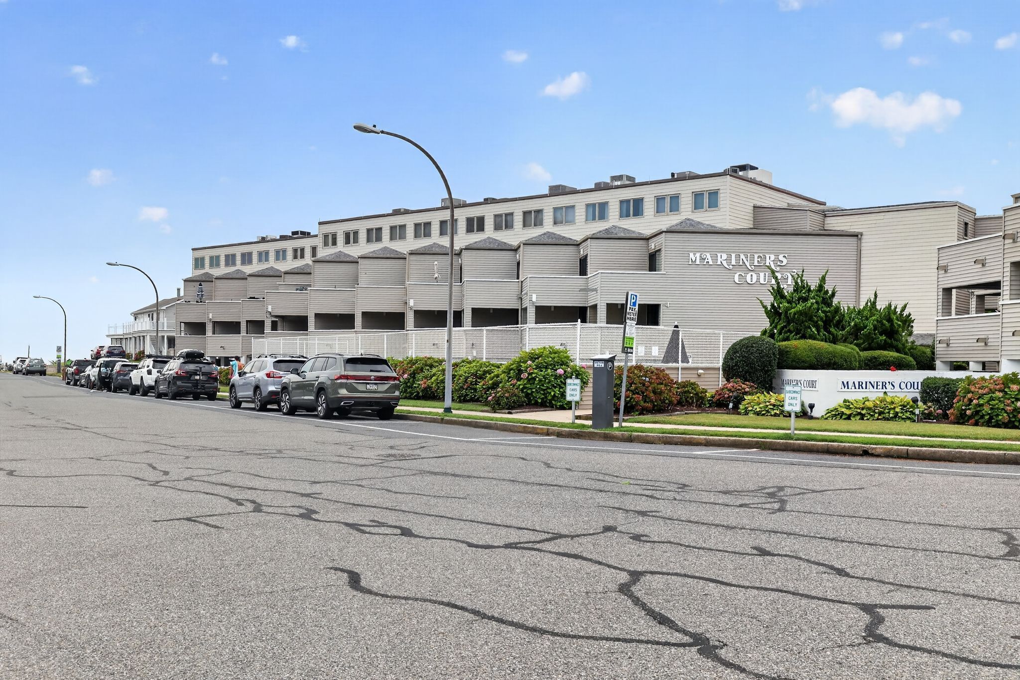 Un parking où sont garées plusieurs voitures et un bâtiment portant l’inscription « Mariners Court ».