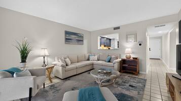 A modern living room with a sectional sofa, a glass coffee table, and a small side table.
