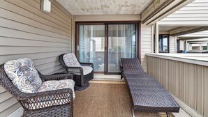 A balcony with wicker furniture, a sliding glass door, and a view of the neighborhood. - South Rehoboth | Ocean Block | Parking (Rehoboth Beach)