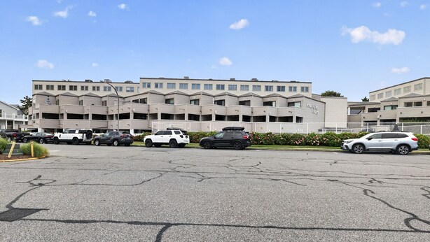 A parking lot with several cars parked in front of a multi-story building with a modern architectural design. - South Rehoboth | Ocean Block | Parking (Rehoboth Beach)