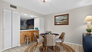 A dining area with a round table, four chairs, a rug, a painting, and a lamp. - South Rehoboth | Ocean Block | Parking (Rehoboth Beach)