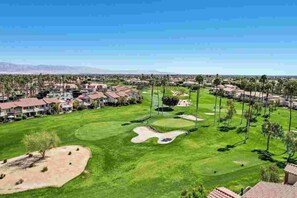 A golf course with sand bunkers, palm trees, and residential buildings in the background. - Remodeled 1-Bedroom on the Palm Royale Country Club Golf Course in La Quinta (La Quinta)