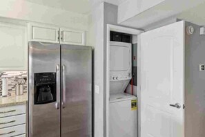 A kitchen with a stainless steel refrigerator, a built-in coffee maker, and a white washing machine. - Remodeled 1-Bedroom on the Palm Royale Country Club Golf Course in La Quinta (La Quinta)