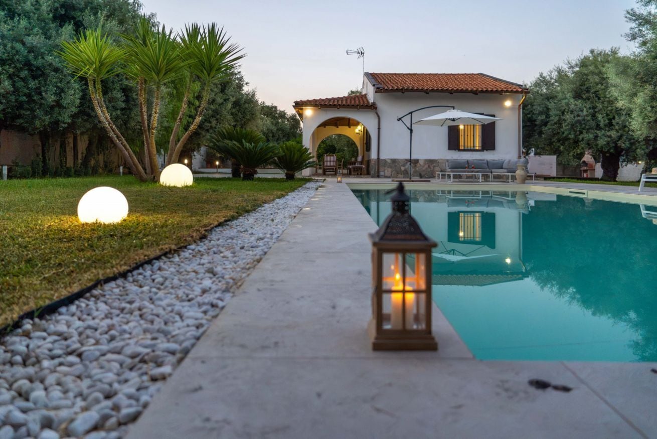 Un área de piscina con un sendero, un farol y un edificio con techo de tejas.