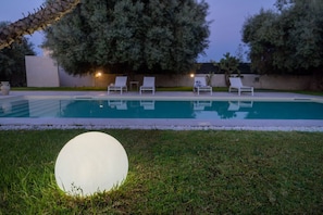 Ein Swimmingpool mit Liegestühlen und einer großen, beleuchteten Kugel im Vordergrund.