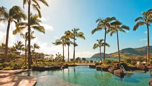 A pool with clear water, surrounded by palm trees and a view of the ocean. - Luxury Ocean View Marriott's Kauai Lagoons - 2BR/2BA villa. Sleeps 6. (Lihue)