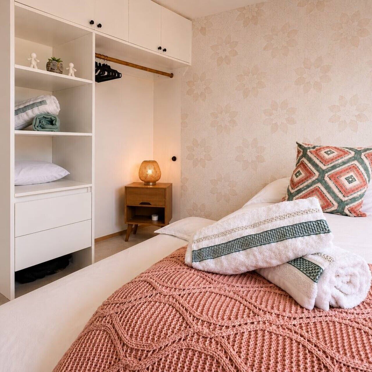 Een slaapkamer met een bed, een kledingkast, een nachtkastje en een lamp.