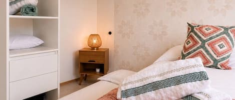 A bedroom with a bed, a wardrobe, a nightstand, and a lamp.