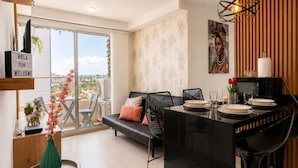 Ein modernes Wohnzimmer mit Essbereich, einer Couch, einem Couchtisch und Blick durch große Fenster.