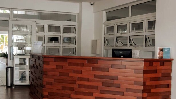 A reception desk with a brick-patterned design, a glass display case, and a computer monitor. - Beach Apartment in Juan Dolio, Getaway Offer (Playa Juan Dolio)
