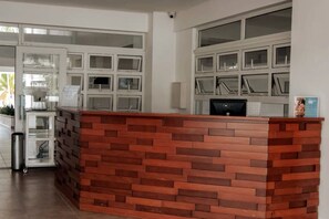 A reception desk with a brick-patterned design, a glass display case, and a computer monitor. - Beachfront Apartment in Juan Dolio, Getaway Offer! (Playa Juan Dolio)