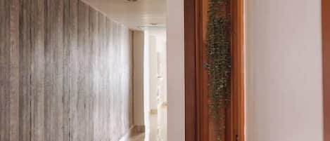 Un pasillo con una puerta de madera y una pared con líneas verticales.
