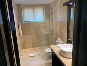Ein modernes Badezimmer mit Duschkabine aus Glas, Toilette, Waschbecken mit großem Spiegel und Handtuchhalter.