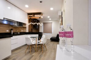 A modern kitchen with white cabinets, a black countertop, and a dining area with a glass table and white chairs. - ¡Cerca de la Macroplaza! 6 personas, Alberca & Gym (Monterrey)