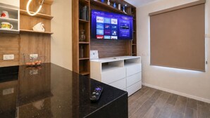 Un menjador modern amb televisió de pantalla plana penjada a la paret de fusta, un comandament sobre la tauleta i una porta corredissa.
