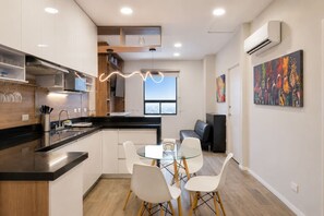 A modern kitchen with a dining area, a black countertop, white chairs, and a view of the city through a large window. - ¡Cerca de la Macroplaza! 6 personas, Alberca & Gym (Monterrey)