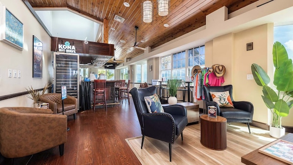 A spacious lobby with wooden flooring, leather seating, a bar area, and large windows offering views.