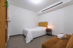 A small, neatly arranged bedroom with a single bed, bedside table, and a small couch. - ¡A pasos de Santa Lucía! 5 beds 3BR2br 8 guests (Monterrey)