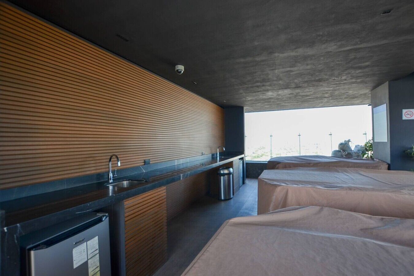A modern kitchen with a wooden panel wall, a sink, and a trash bin.