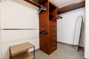 Ein begehbarer Kleiderschrank mit Holzschrank, Metallkleiderbügelstange und einem kleinen Holztisch.