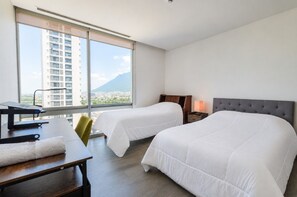 A hotel room with two beds, a desk, and a view of a cityscape and mountain. - ¡A pasos de Santa Lucía! 5 beds 3BR2br 8 guests (Monterrey)