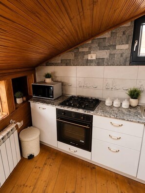 Eine kleine Küche mit Steinrückwand, Holzboden und integrierten Geräten.
