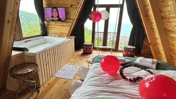 Una habitación de madera con cama, ventana con cortinas, bañera y globos.