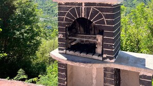 A brick-built outdoor oven with a chimney, set against a backdrop of green hills and a clear sky. - Emis Dağ Evi (Findikli)