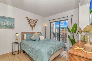 Ein Schlafzimmer mit einem Bett, einem Nachttisch, einer Lampe, einem Gemälde, Wanddekoration und einem Balkon mit Pflanzen.
