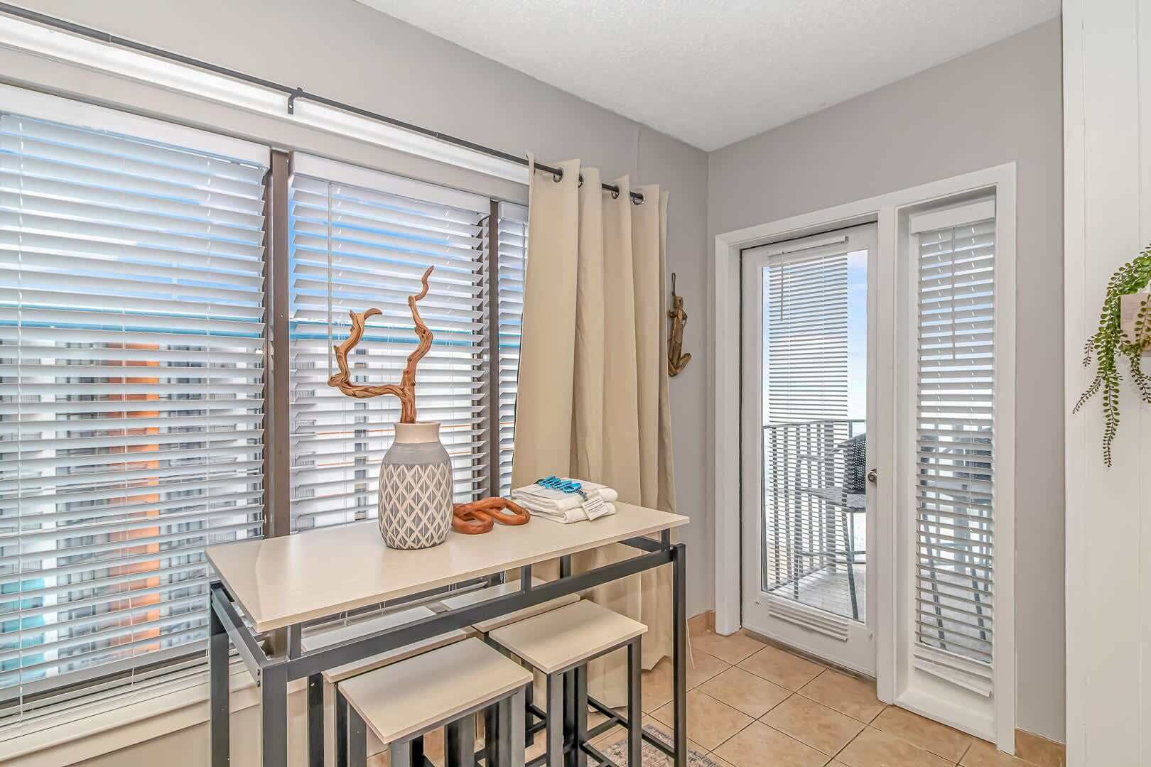 A room with a dining table, chairs, a vase with a branch, and a towel rack.