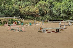 Una arena ecuestre al aire libre con obstáculos y superficie de arena.