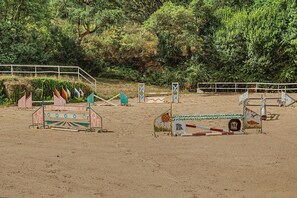 Ein offenes Reitgelände mit Hindernissen und Sandboden.