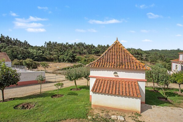 A small building with a tiled roof, surrounded by a grassy area and trees.