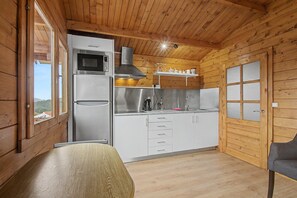 Eine kleine Küche mit Mikrowelle, Herd und Spüle, Holzwänden und einem Fenster.
