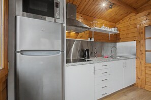 Una cocina compacta con un refrigerador de acero inoxidable, un microondas y un horno empotrado.
