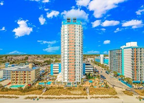 A tall hotel with multiple floors, a swimming pool, and a beach view. - Palace 1909 Ocean View Studio (Myrtle Beach)