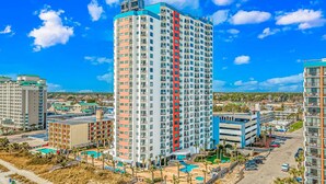 A high-rise hotel with multiple floors, a swimming pool area, and a parking lot. - Palace 1909 Ocean View Studio (Myrtle Beach)