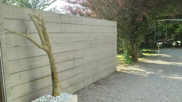 Ein moderner Außenbereich mit Holzzaun, Kiesweg und Baumschale.