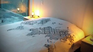 Une chambre avec un grand lit, une table de chevet, une lampe et une vue sur un balcon.