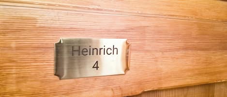 A metallic nameplate with the name 'Heinrich' and the number '4' on a wooden surface.