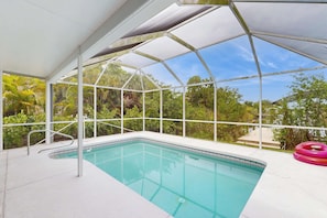 A covered swimming pool with a glass ceiling, surrounded by greenery. - Spacious 3 Bedroom Waterfront Home with Private Pool and in Port Charlotte (Port Charlotte)