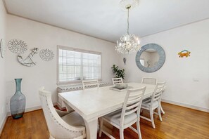 A dining area with a white table and chairs, a chandelier, decorative wall art, and a window with blinds. - Spacious 3 Bedroom Waterfront Home with Private Pool and in Port Charlotte (Port Charlotte)