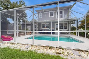 Ein Haus mit Swimmingpool, überdachter Terrasse und großem Fenster mit Blick auf den Pool.